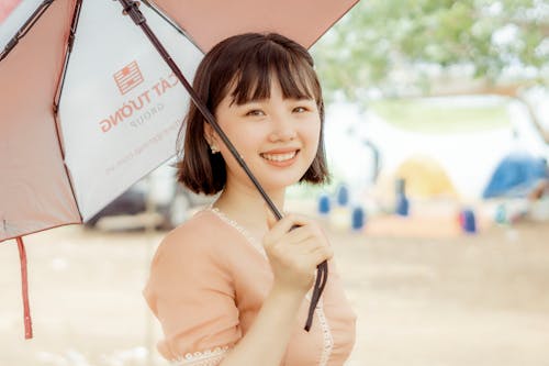 Delighted Asian woman under umbrella in summer