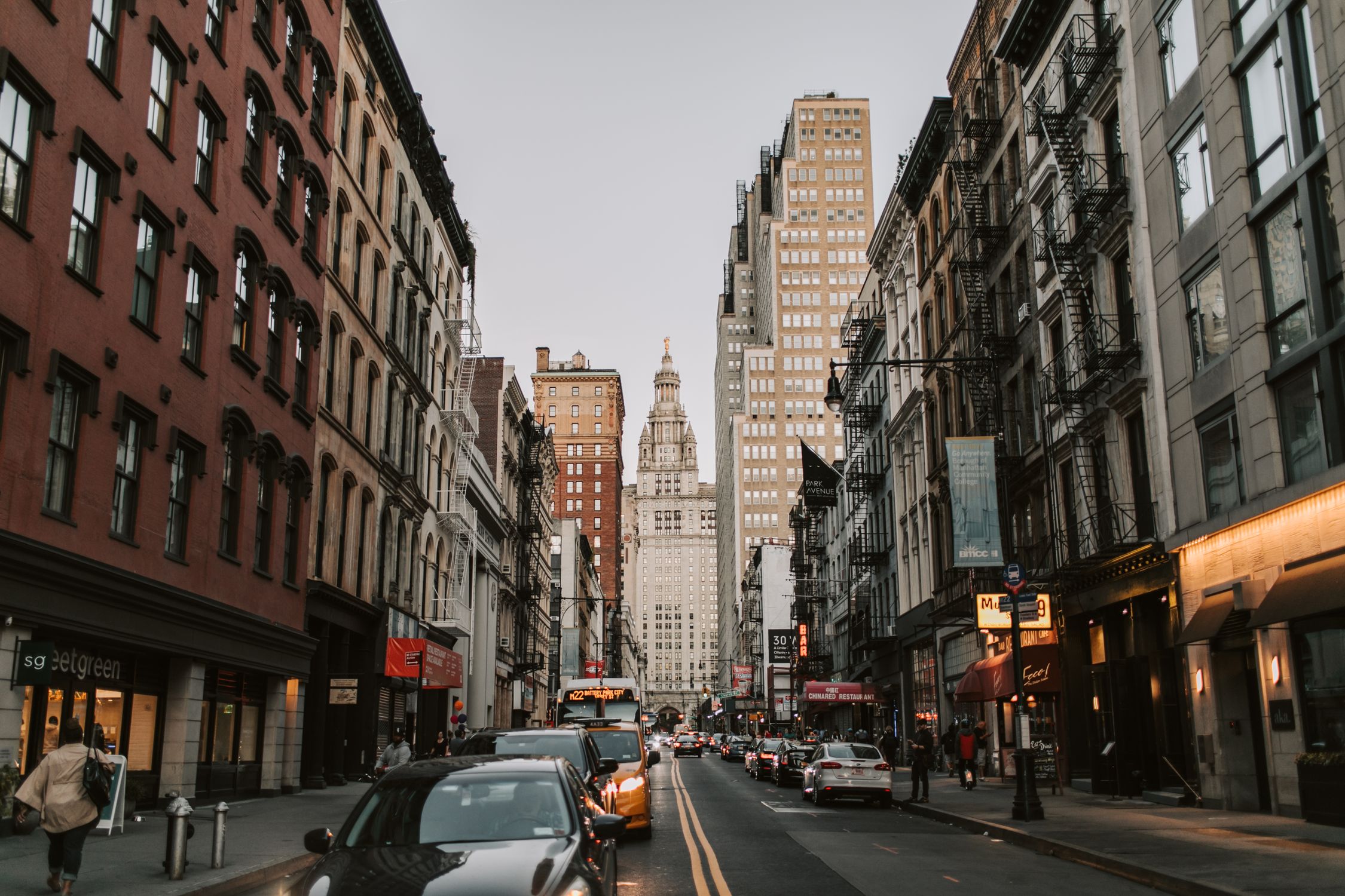Dynamic street scene with historic facades leading to iconic skyscrapers in New York City