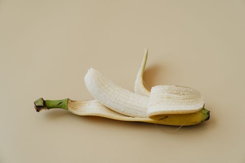 Free A peeled banana displayed on a soft beige background in a minimalist style. Stock Photo