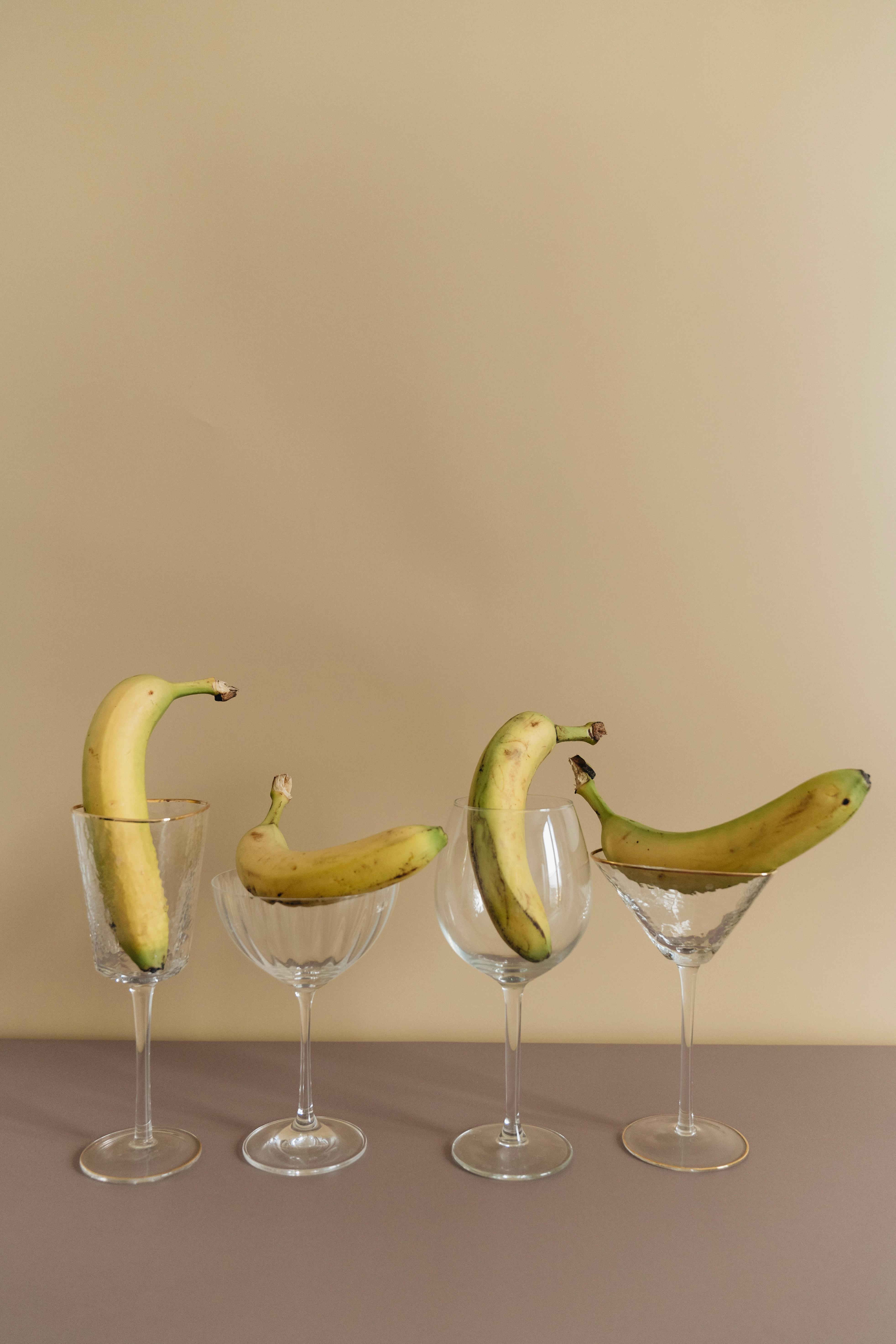 四个香蕉被创造性地置于优雅的酒杯中，展现了极简主义的美食艺术