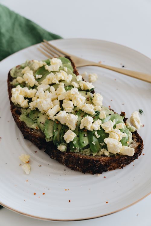 Free Delicious slice of avocado toast topped with crumbled feta cheese, perfect for a nutritious lunch. Stock Photo
