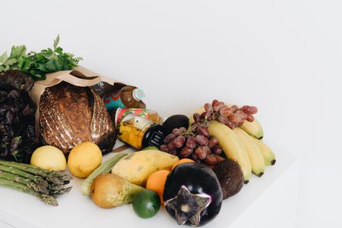 Free A colorful assortment of fresh fruits and vegetables including bread and organic produce on a white background. Stock Photo