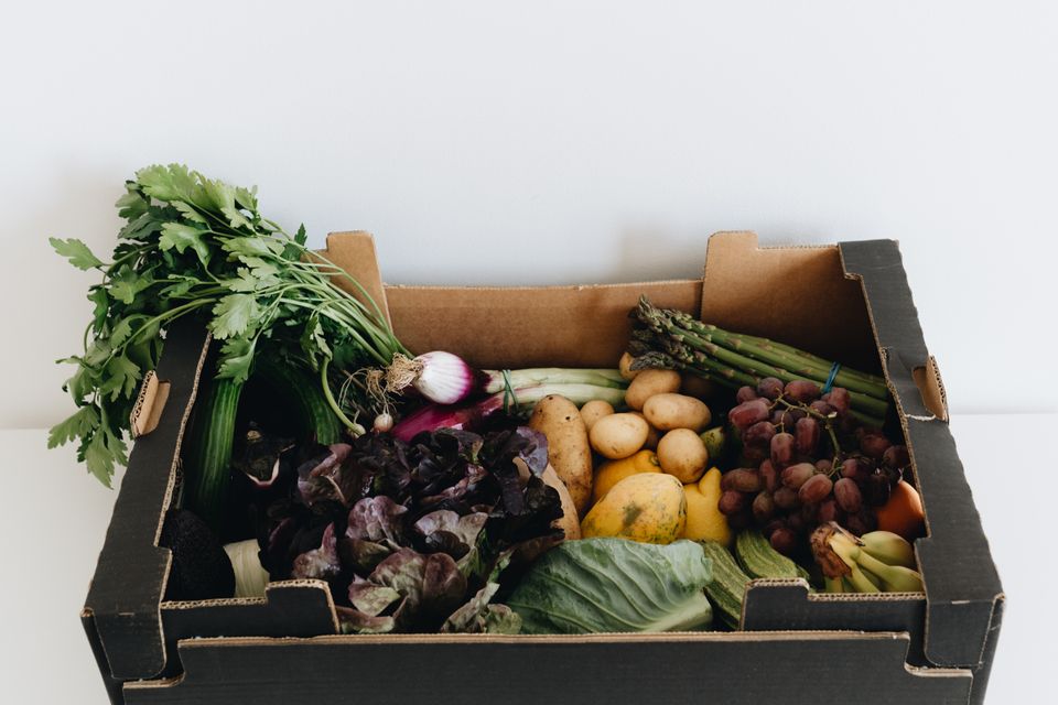 A delivery box packed with fresh greens, potatoes, grapes and herbs — photo by alleksana on Pexels