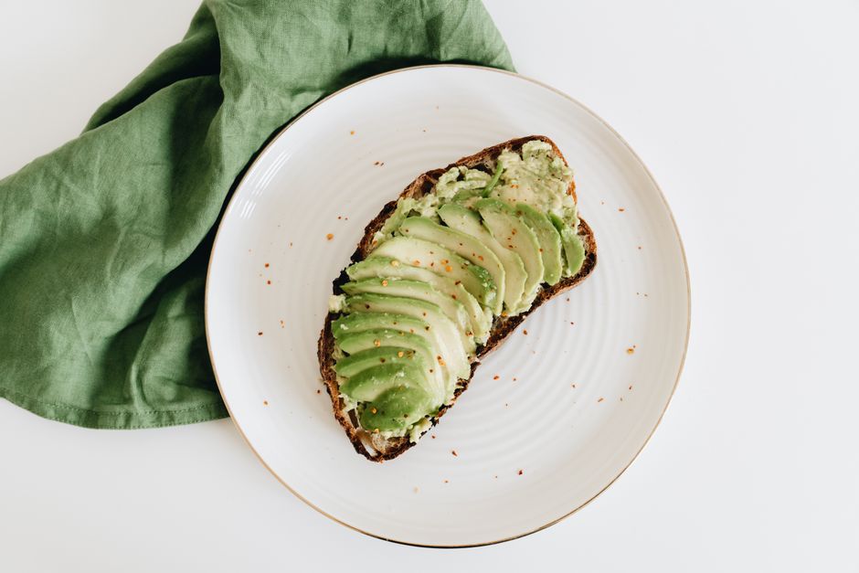 Tasty avocado toast served on a white plate with a green napkin, perfect for breakfast or brunch.
