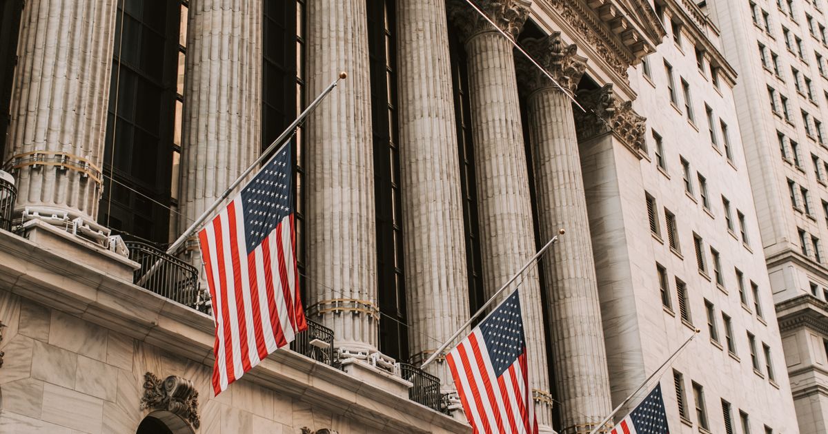 The New York Stock Exchange with American flags hanging on its facade.