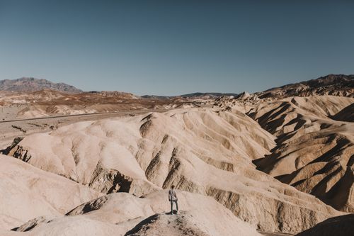 Free A lone traveler stands amidst the arid landscape of Death Valley. Stock Photo