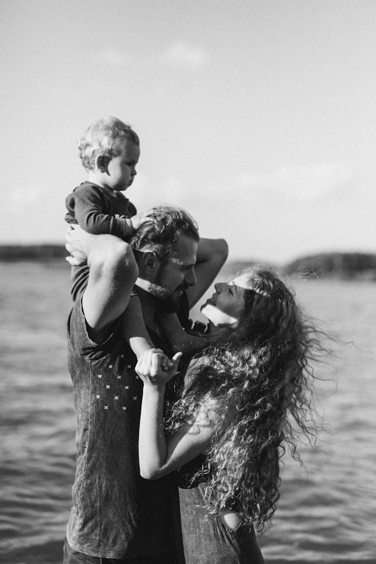 Grayscale Photo Of A Man Carrying A Child On His Back