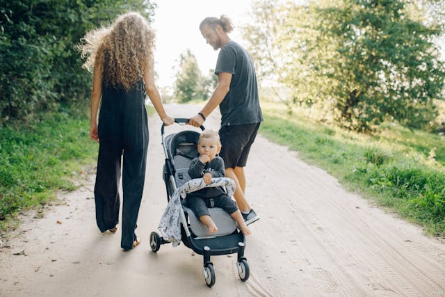 Happy family walking in the park with baby stroller