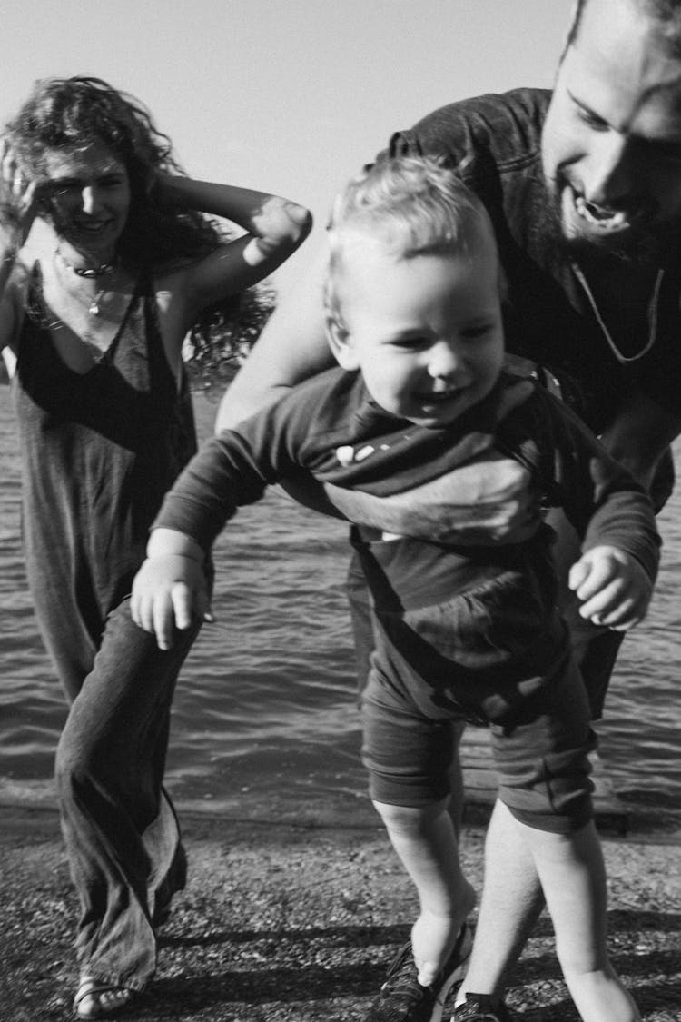 Black And White Photo Of A Happy Family Walking On The Shore Of A Beach