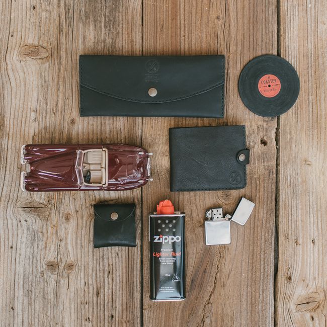 Flat lay of vintage items including leather wallets, a model car, and lighter on wooden planks.