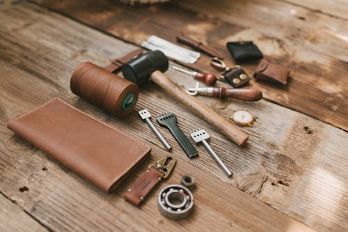 A Leather Wallet and Tools for Leather Crafting Lying on a Wooden Surface