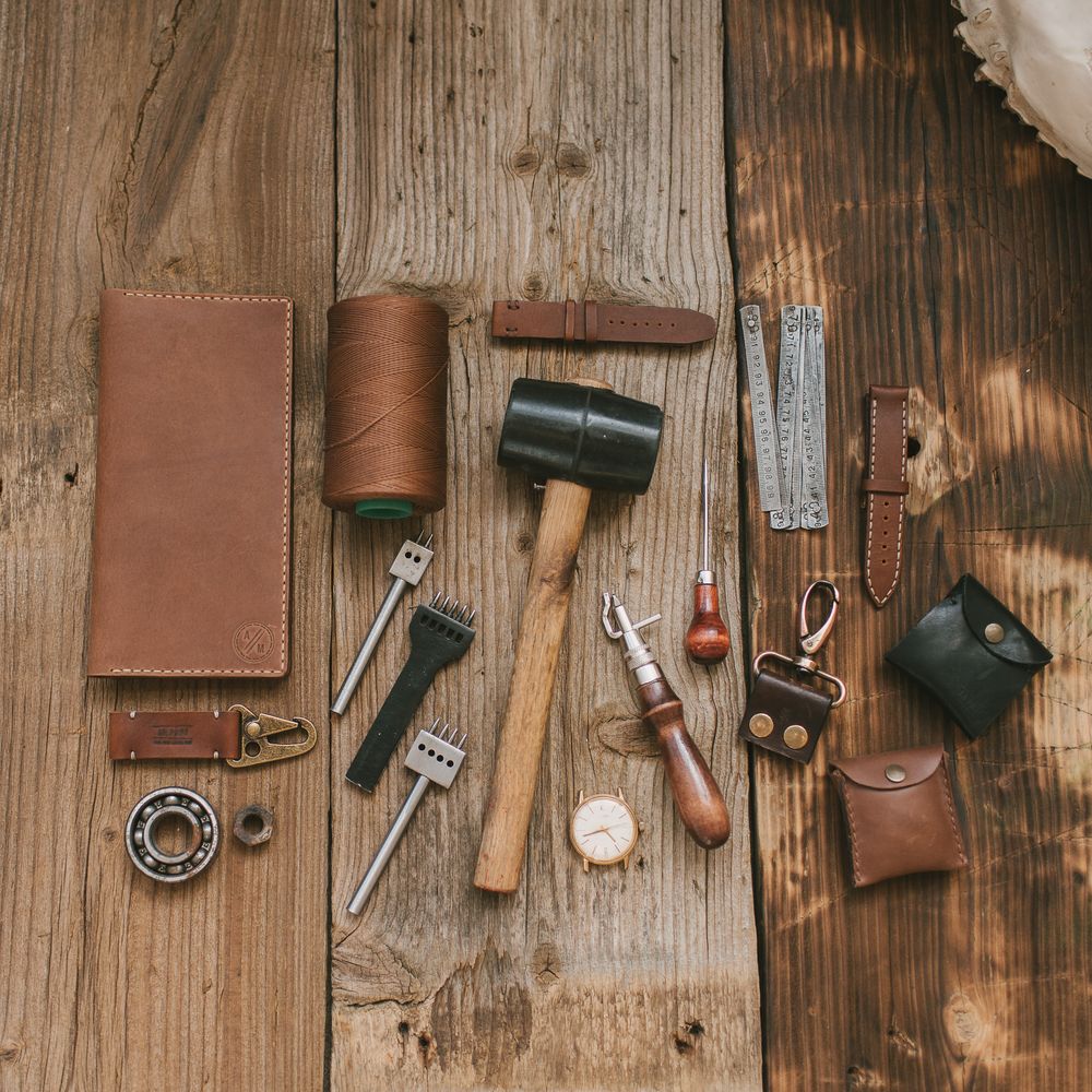 Leatherworking tools arranged on a wooden workbench