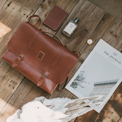 A Brown Leather Briefcase and Wallet Lying on a Wooden Surface