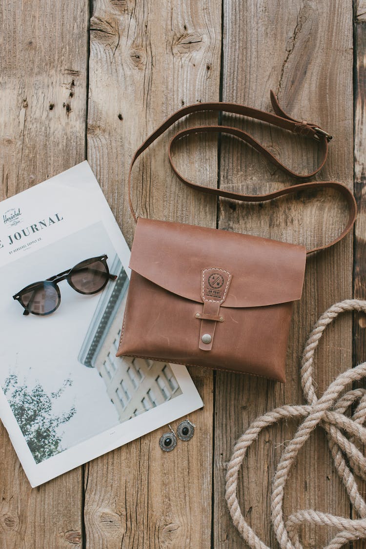 Brown Leather Sling Bag Sunglasses On The Wooden Table