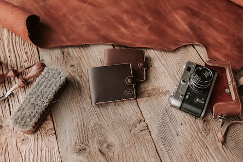 Handmade Leather Wallets and a Film Camera Lying on a Wooden Surface 