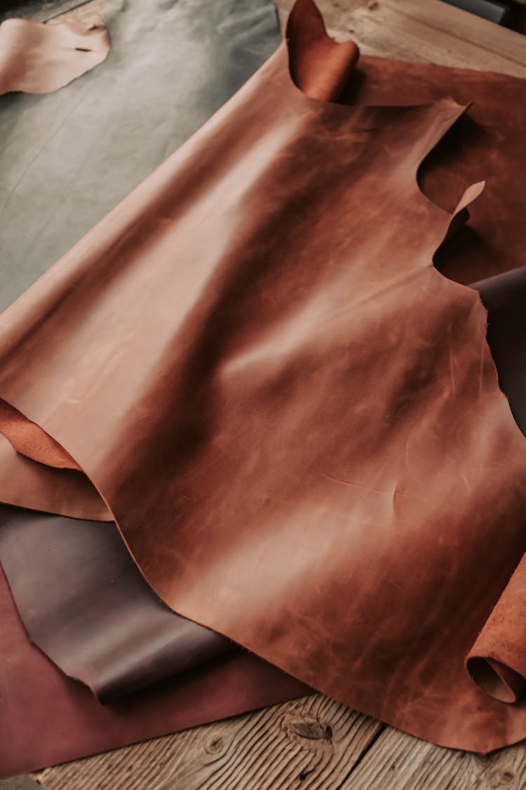 Sheets Of Brown Leather Lying On A Wooden Surface