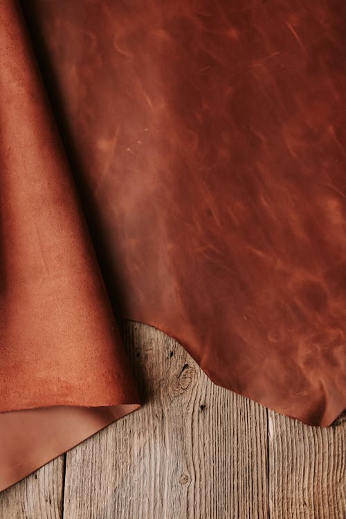 Close-up of a Sheet of Brown Leather Lying on a Wooden Surface