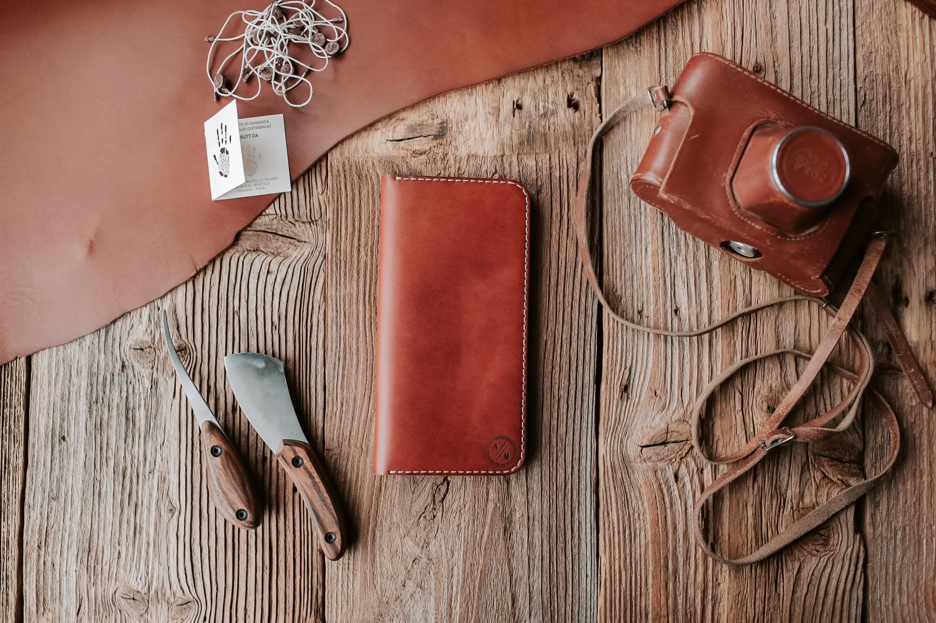 A stylish flat lay of leather items, tools, and camera on rustic wooden background.
