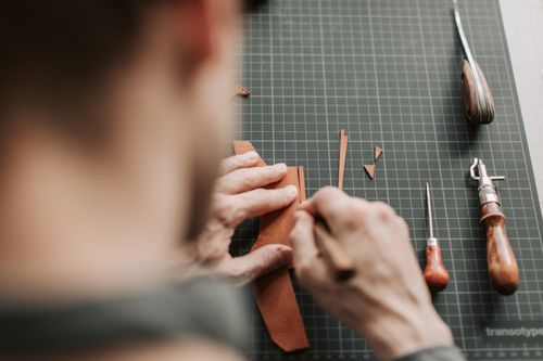 Free Close-up of a craftsman cutting leather with tools in a workshop setting. Stock Photo