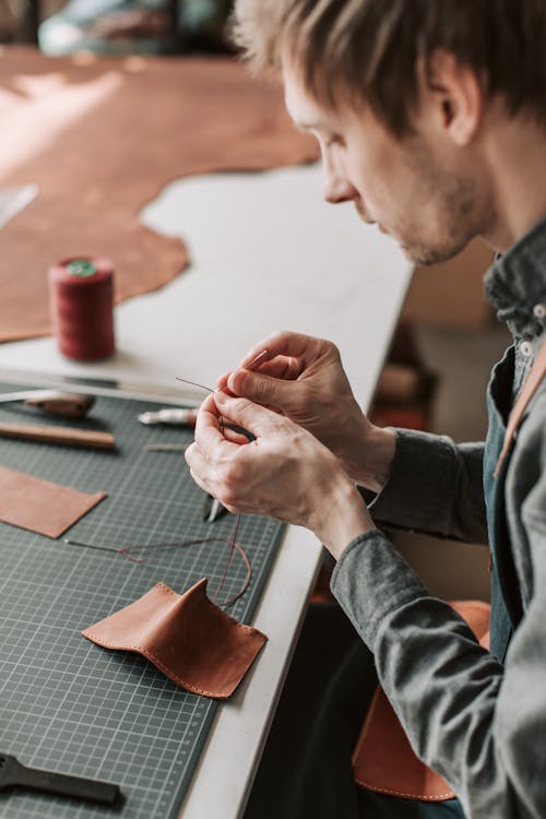 Man in Gray Long Sleeves Working with Leather