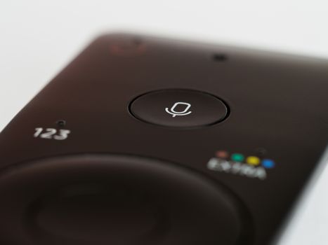Close-up of a remote control featuring a prominent microphone button, suitable for voice commands.