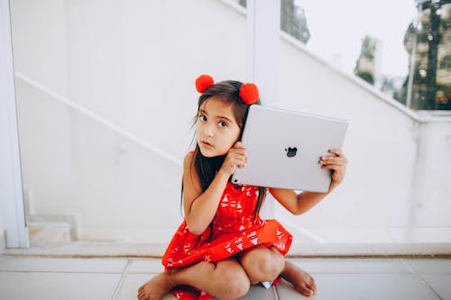 Girl in Red Dress Sitting While Holding Silver Ipad Pro