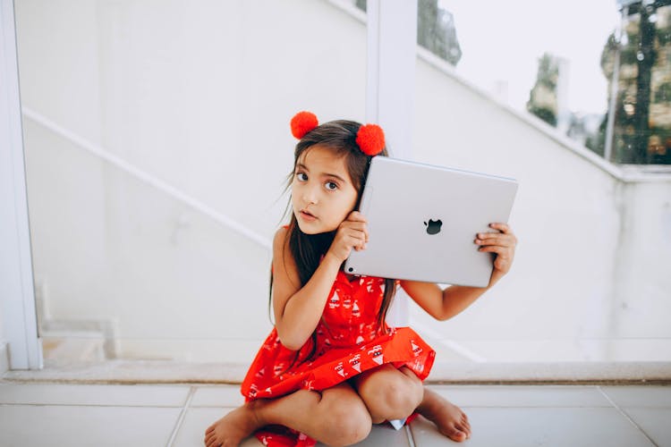 Girl In Red Dress Sitting While Holding Silver Ipad Pro