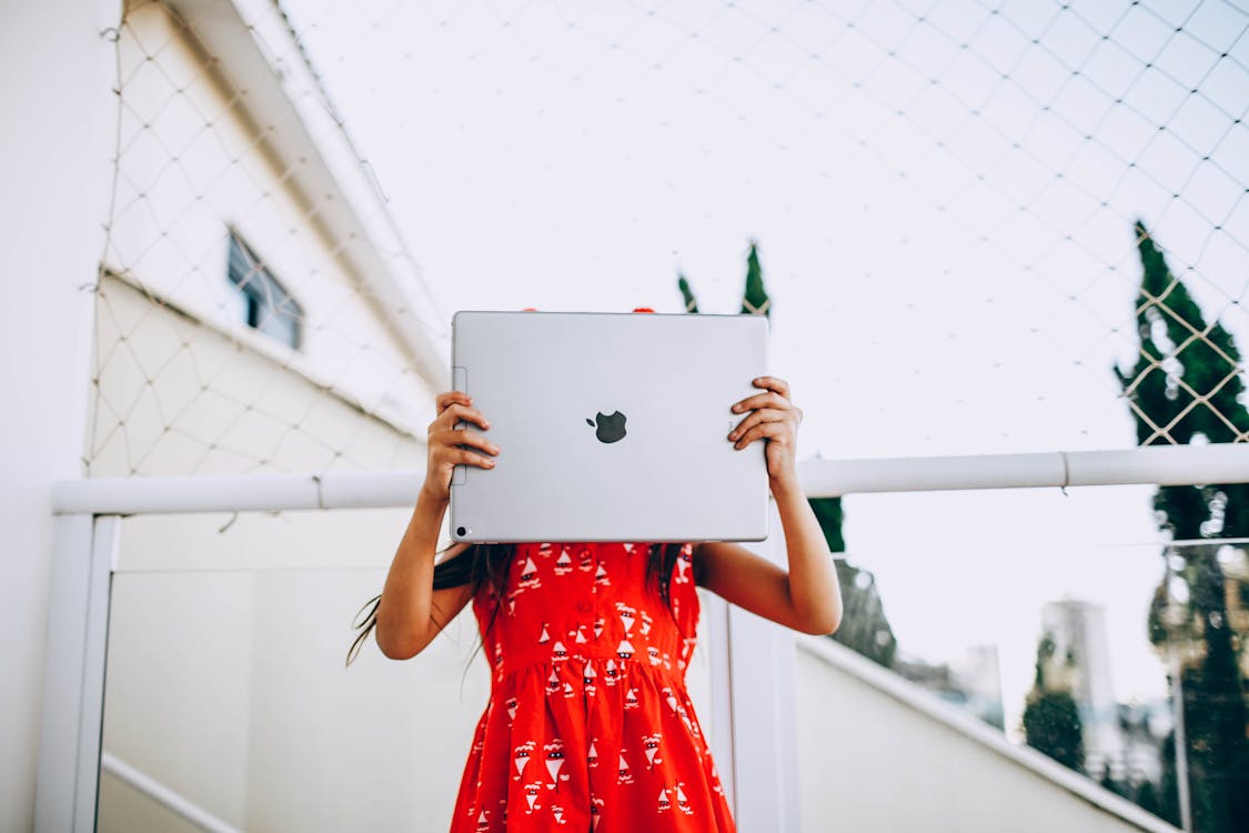 Woman in Red Dress Holding Silver Macbook