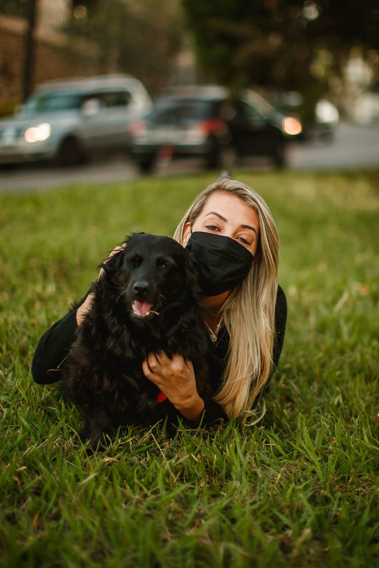 Woman In Mask With Dog On Meadow