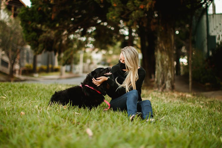 Woman Caressing Dog On Lawn