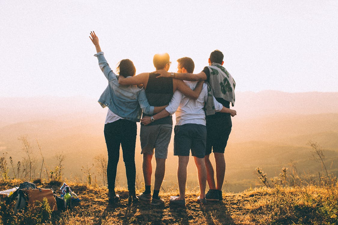 Free Anonymous friends standing together at sunset in mountains Stock Photo