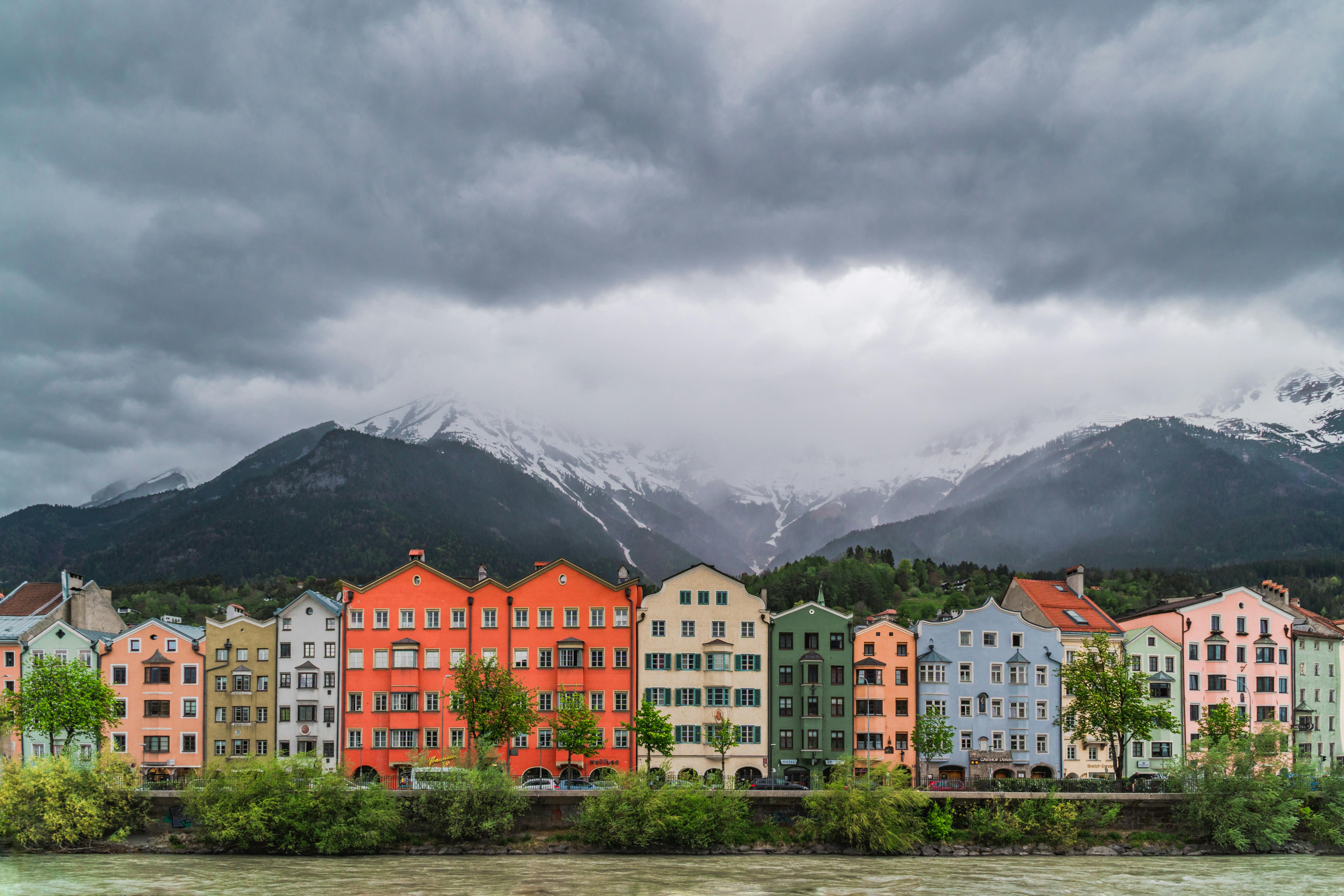 White and Brown Concrete Buildings Near Green Trees and Mountains Under White Clouds