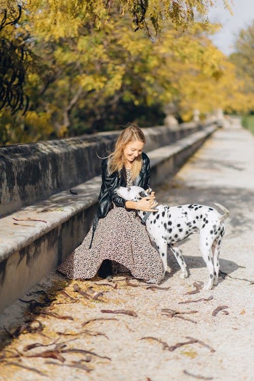 
A Woman in Leather Jacket Petting a Dalmatian