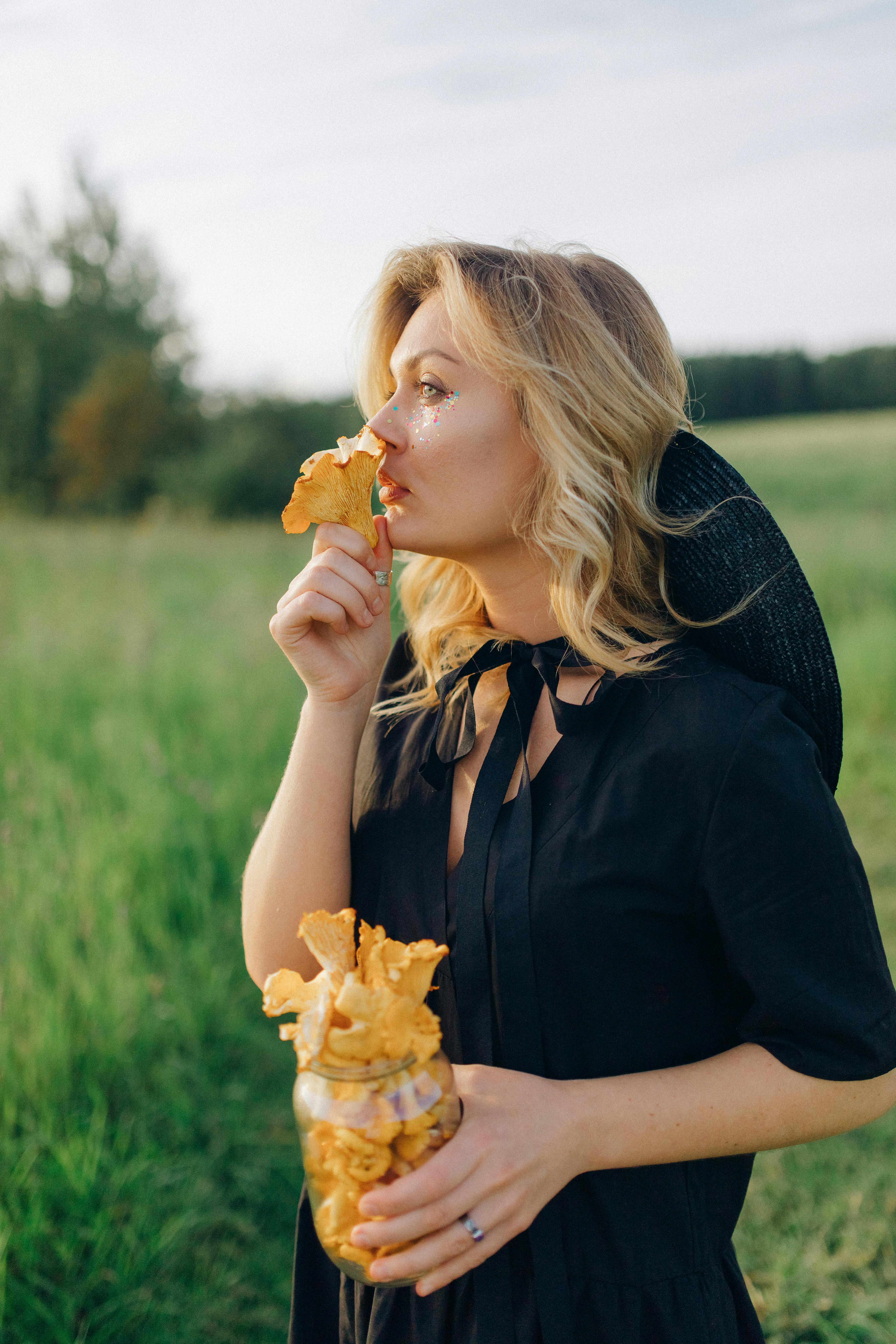 girl in black long sleeve shirt eating yellow flower