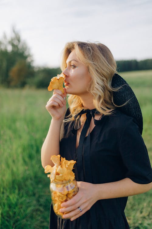 Girl in Black Long Sleeve Shirt Eating Yellow Flower