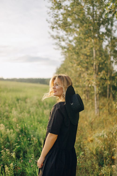 Woman in Black T-shirt Standing on Green Grass Field