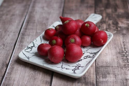 Bright raw radishes on plate in rustic house