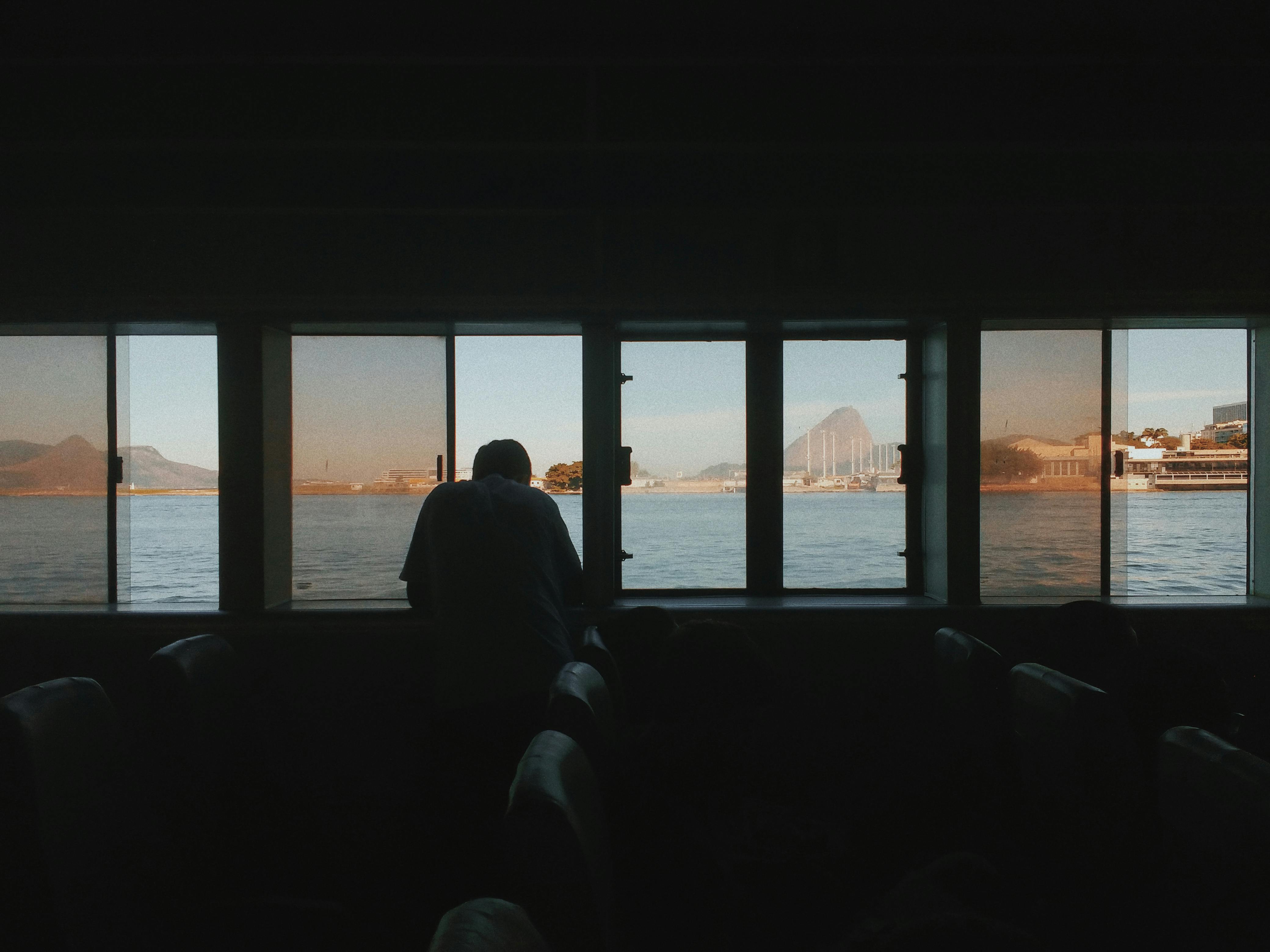 silhouette of man sitting on chair near body of water