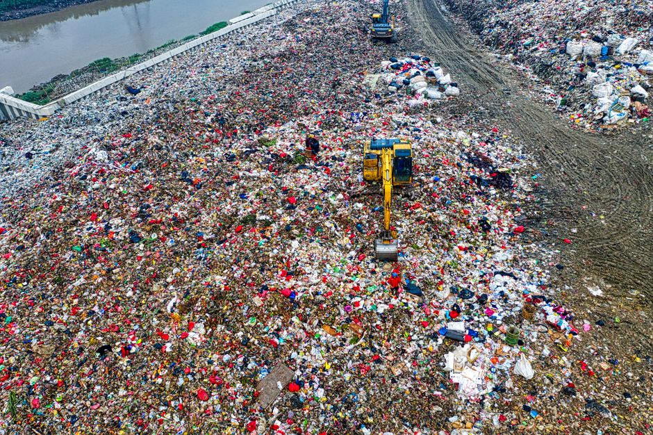 Photo by Tom Fisk Birds-eye view of a bustling landfill in Banten with excavators working amidst the piles of waste.
