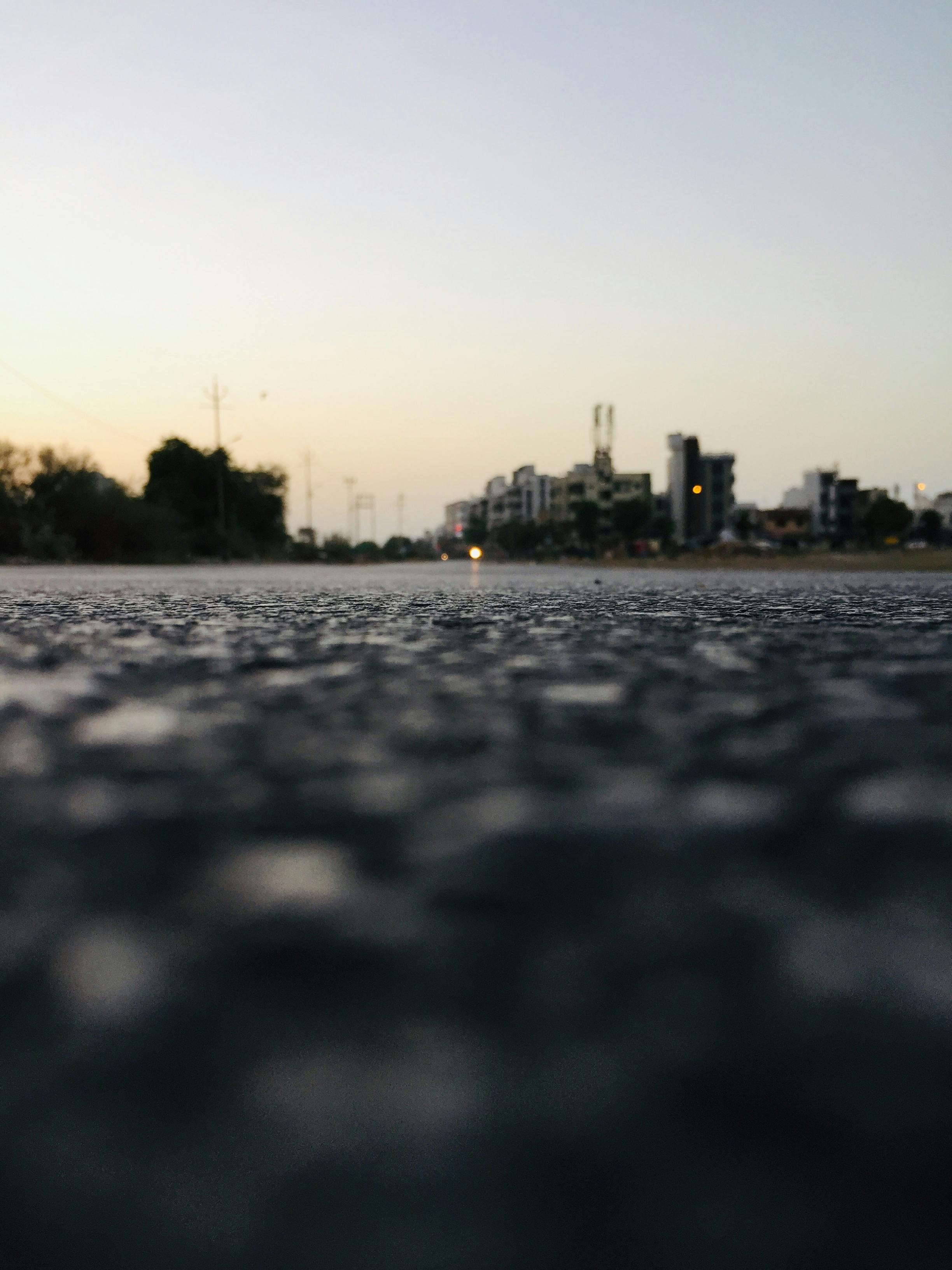 Low angle view of an urban road in Vadodara, India with buildings in the background at dusk. | Indian Village Development