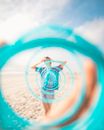 Unrecognizable traveler on sandy beach in front of toy rainbow