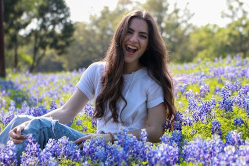 Young Happy Woman Sitting on a Field with Bluebonnets 