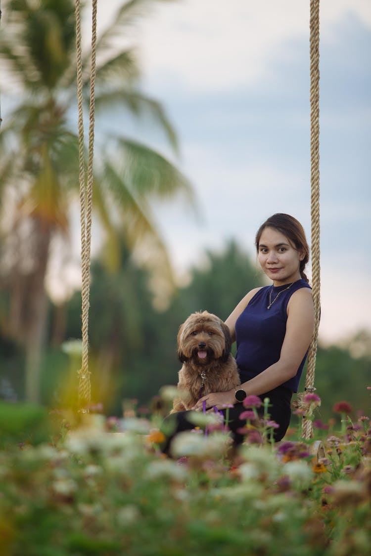 Ethnic Woman Carrying Small Fluffy Dog In Park