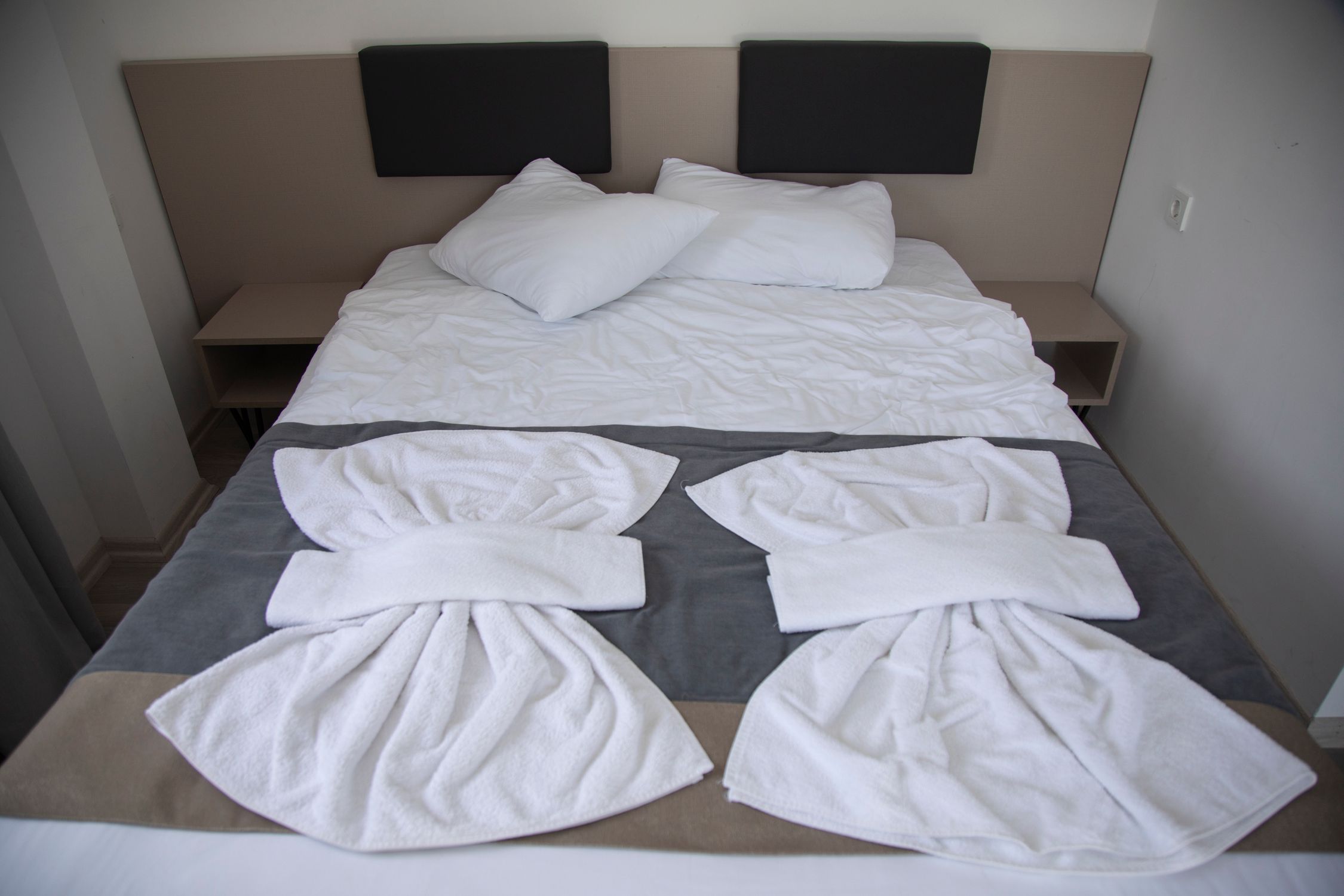 Hotel bedroom with neatly arranged bed and artistic towel design, creating a welcoming ambiance.