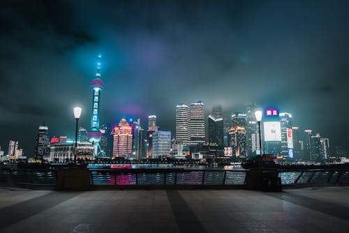 Modern skyscrapers illuminated by street lights under sky in evening