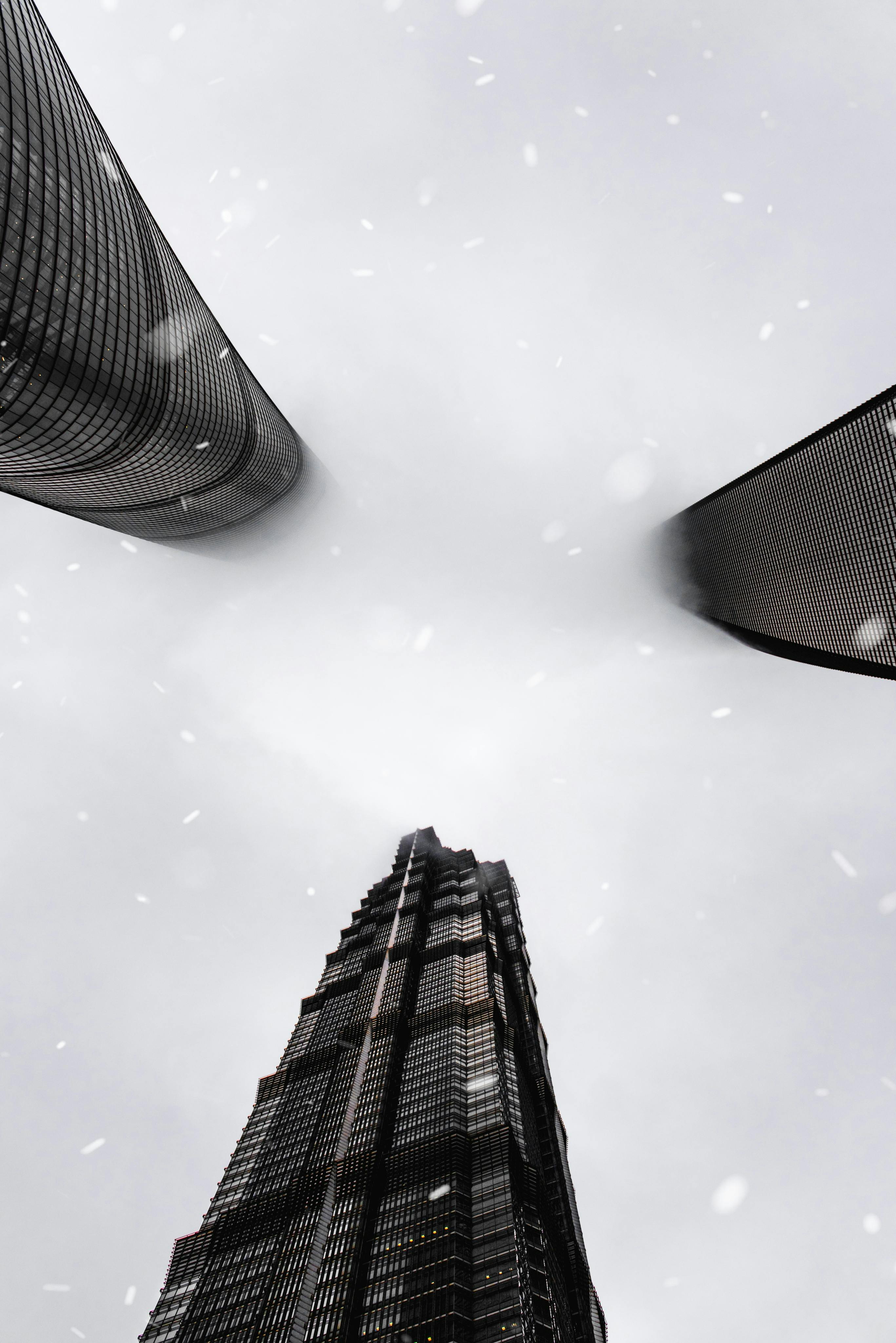 From below of contemporary multistory building facades under white sky in mist in town