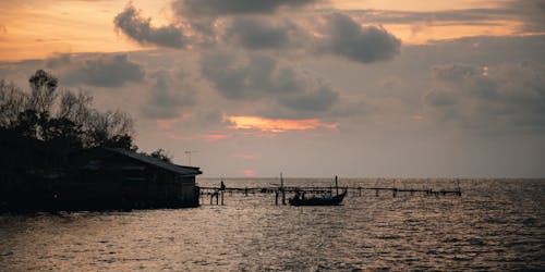 Silhouette of Boat on Sea Near Wooden Dock