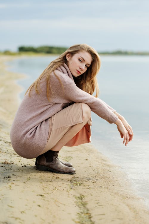 Woman in Brown Sweater Squatting Near Water