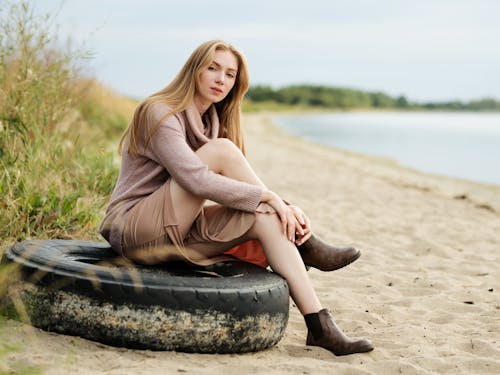 Woman in Brown Sweater and Skirt Sitting on a Tire