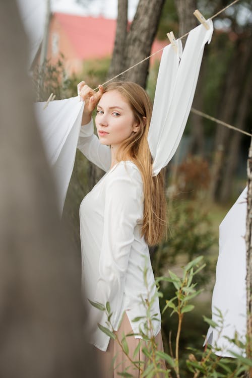 Woman in White Long Sleeve Shirt Holding a String with Hanging Clothes